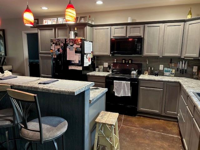 kitchen featuring light stone counters, pendant lighting, black appliances, a breakfast bar, and decorative backsplash