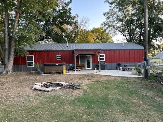 back of property with a patio area, a yard, and a hot tub