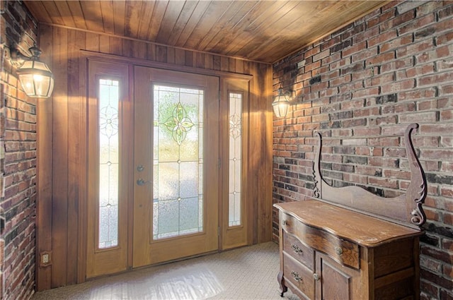 doorway with light carpet, wood walls, wooden ceiling, and brick wall