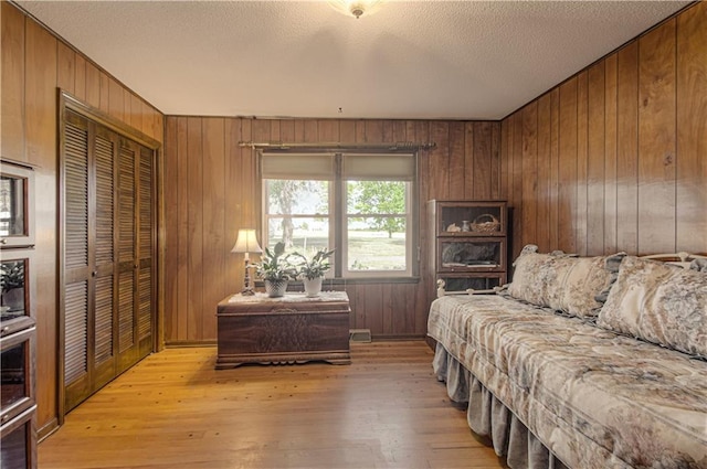 living room featuring wood walls, a textured ceiling, and light hardwood / wood-style flooring