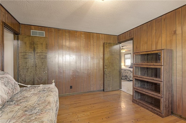 living area featuring wooden walls, light hardwood / wood-style flooring, and a textured ceiling