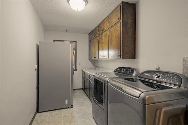 laundry room featuring washer and dryer, a textured ceiling, and cabinets