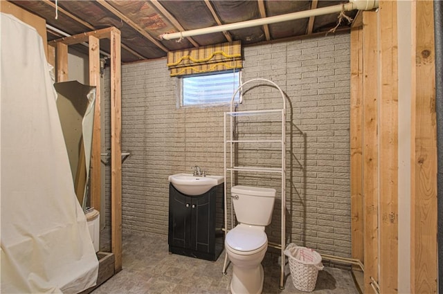 bathroom with vanity, toilet, brick wall, and a shower with shower curtain