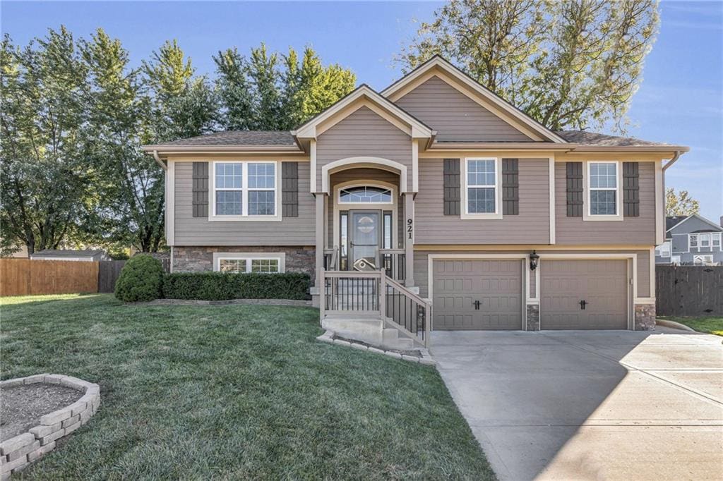 raised ranch featuring a front lawn and a garage