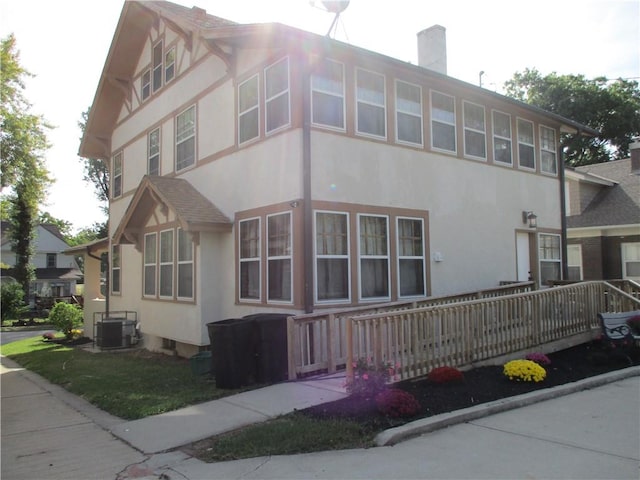 exterior space with central air condition unit, a chimney, and stucco siding