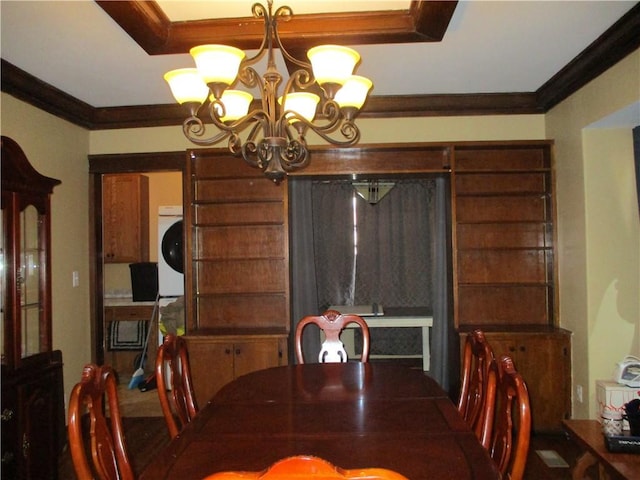 dining room featuring stacked washer / dryer, a chandelier, and crown molding