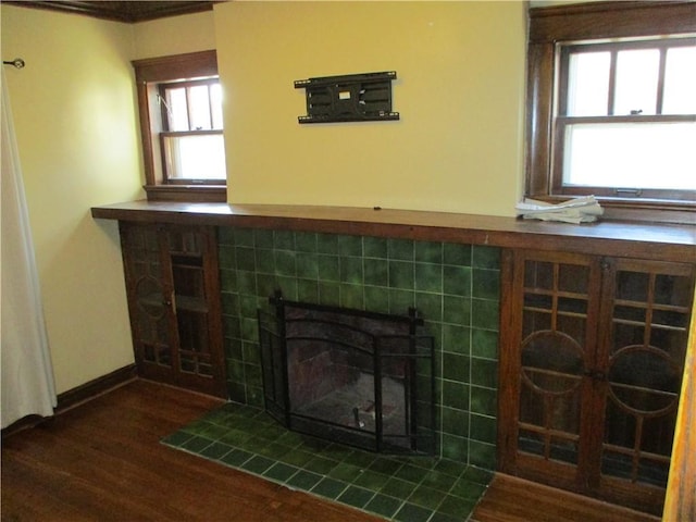 room details with a tiled fireplace, baseboards, and wood finished floors