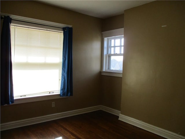 unfurnished room featuring baseboards and dark wood-style flooring