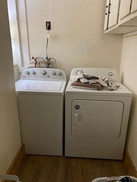 laundry room featuring cabinets, dark hardwood / wood-style floors, and washing machine and clothes dryer