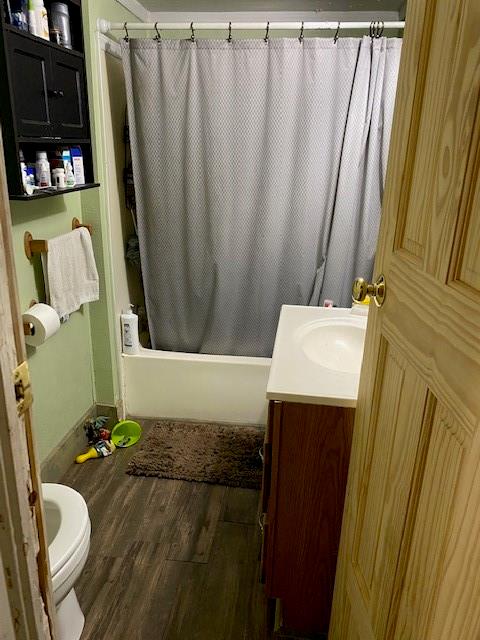 full bathroom featuring shower / tub combo with curtain, hardwood / wood-style flooring, vanity, and toilet