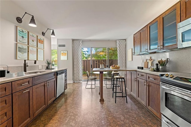 kitchen with light countertops, visible vents, appliances with stainless steel finishes, brown cabinetry, and a sink