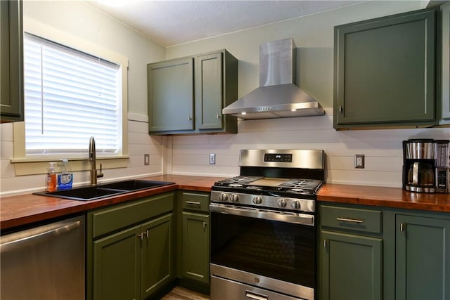 kitchen featuring wall chimney range hood, appliances with stainless steel finishes, sink, and wood counters