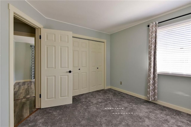 unfurnished bedroom with a closet and dark carpet
