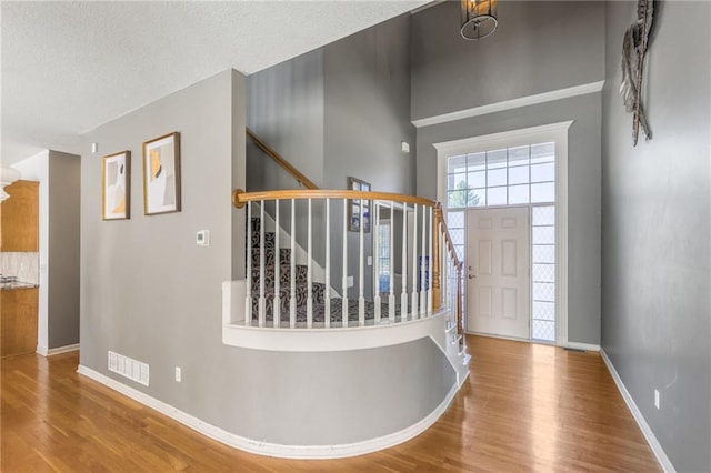 entryway with an inviting chandelier, hardwood / wood-style floors, and a textured ceiling