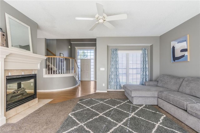 living room featuring a tiled fireplace, wood-type flooring, and ceiling fan