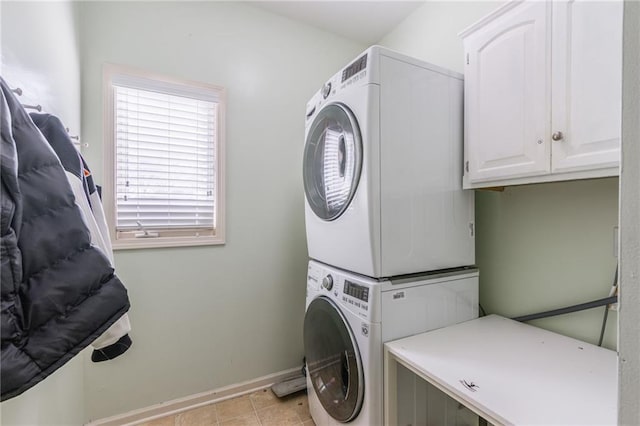 laundry room with cabinets, stacked washing maching and dryer, and light tile patterned floors