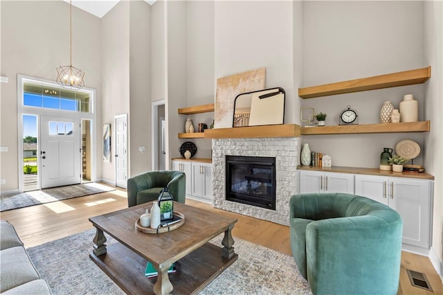 7016 N Polk Ave, Kansas City, MO 64151 - living room with a towering ceiling, a chandelier, light wood-style flooring, and a glass covered fireplace