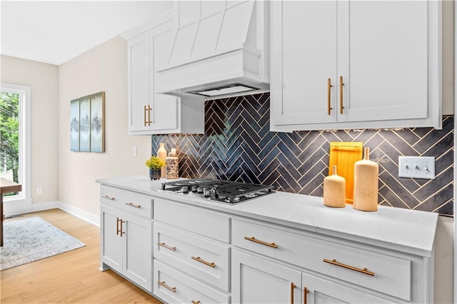 7016 N Polk Ave, Kansas City, MO 64151 - kitchen with custom range hood, tasteful backsplash, light countertops, stainless steel gas stovetop, and light wood-style flooring