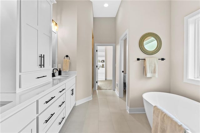 7016 N Polk Ave, Kansas City, MO 64151 - full bathroom with baseboards, a soaking tub, vanity, toilet, and tile patterned flooring