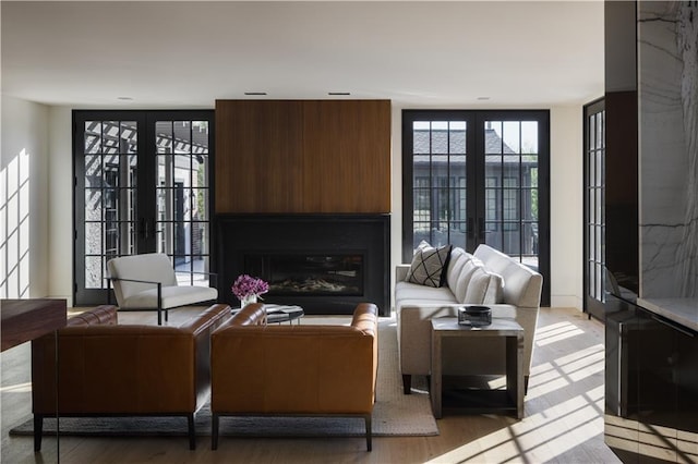 living room featuring french doors, a fireplace, and light wood-type flooring