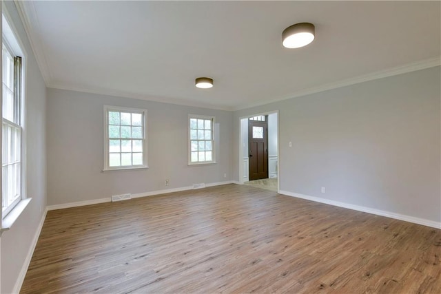 spare room with light wood-type flooring and crown molding