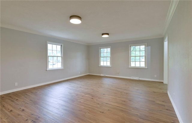 empty room with light wood-type flooring, crown molding, and plenty of natural light