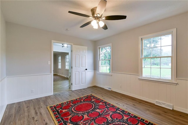 empty room featuring a healthy amount of sunlight, ceiling fan, and light hardwood / wood-style floors