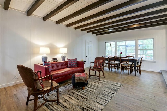 living room with light wood-type flooring, beamed ceiling, and wooden walls