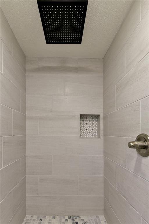 bathroom with a textured ceiling and tiled shower