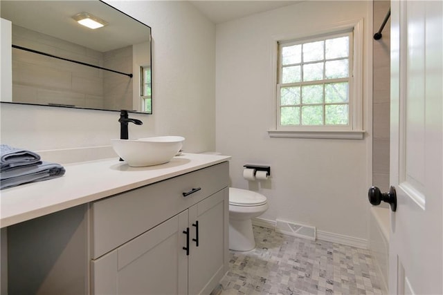 bathroom featuring a tile shower, toilet, and vanity