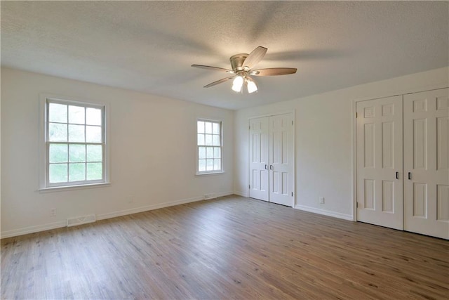 unfurnished bedroom with multiple closets, hardwood / wood-style floors, and multiple windows