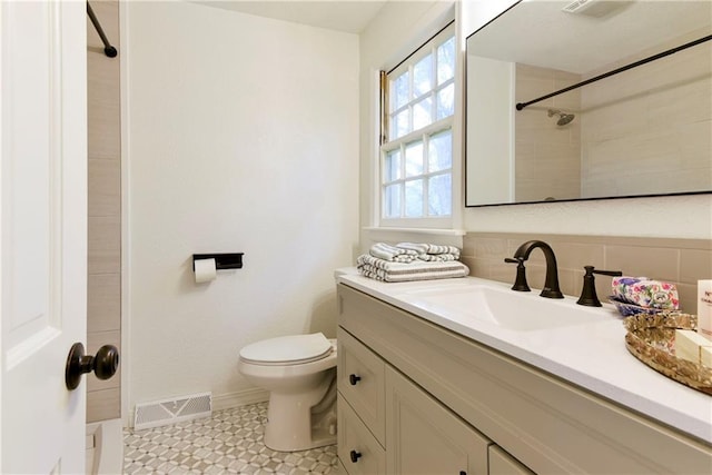 bathroom featuring tile patterned flooring, a tile shower, vanity, and toilet