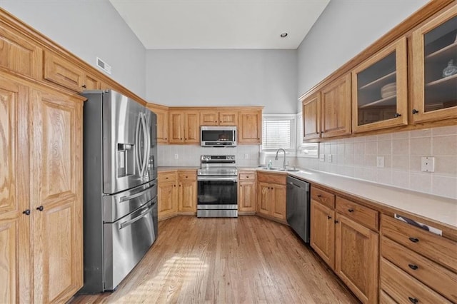 kitchen with sink, light hardwood / wood-style flooring, stainless steel appliances, and backsplash