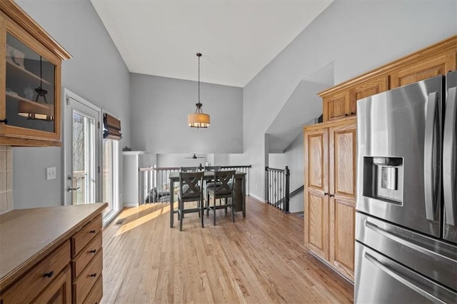 kitchen with hanging light fixtures, stainless steel fridge with ice dispenser, light hardwood / wood-style flooring, and high vaulted ceiling