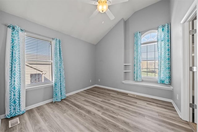 spare room with lofted ceiling, light wood-type flooring, and a healthy amount of sunlight