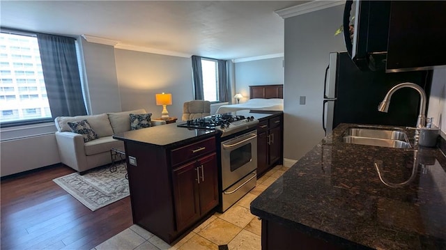 kitchen with stainless steel range with gas cooktop, a healthy amount of sunlight, sink, and light wood-type flooring