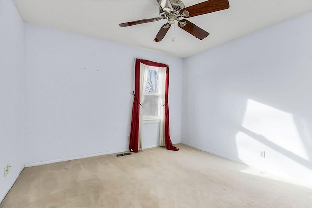 carpeted spare room featuring visible vents, baseboards, and ceiling fan