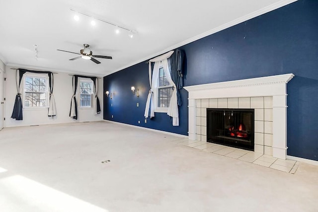 unfurnished living room with baseboards, ornamental molding, a tile fireplace, rail lighting, and a ceiling fan