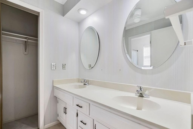 full bath with double vanity, a spacious closet, and a sink