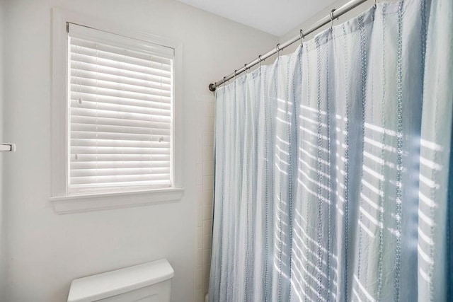 bathroom with a shower with shower curtain, toilet, and a wealth of natural light