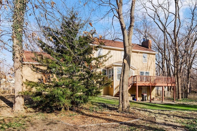 back of house featuring stairway, a deck, and a chimney