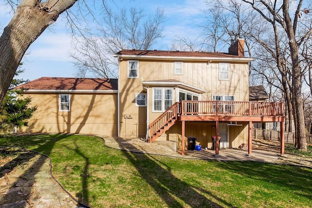 back of house featuring stairway, a chimney, a yard, a deck, and a patio