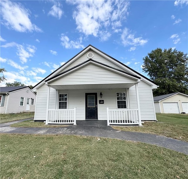 view of front of house featuring a front lawn, covered porch, a garage, and an outdoor structure