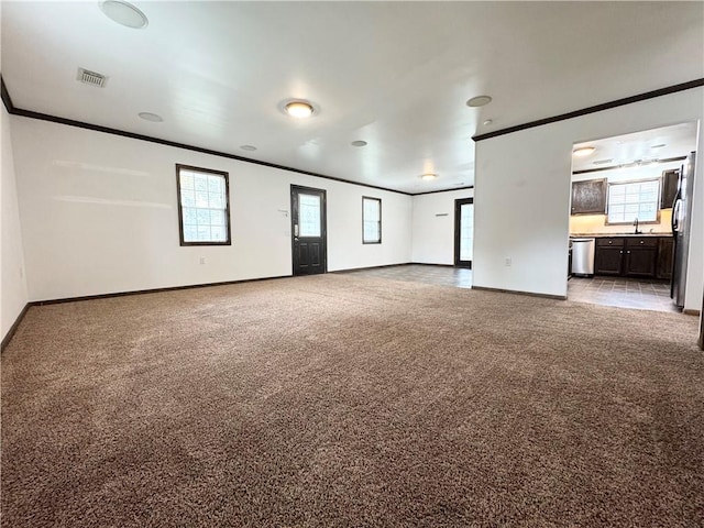 unfurnished living room with ornamental molding, sink, and light colored carpet