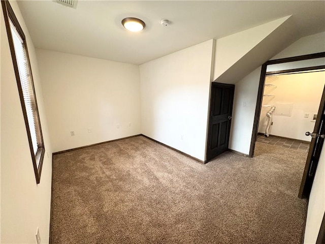 unfurnished bedroom featuring dark carpet and vaulted ceiling