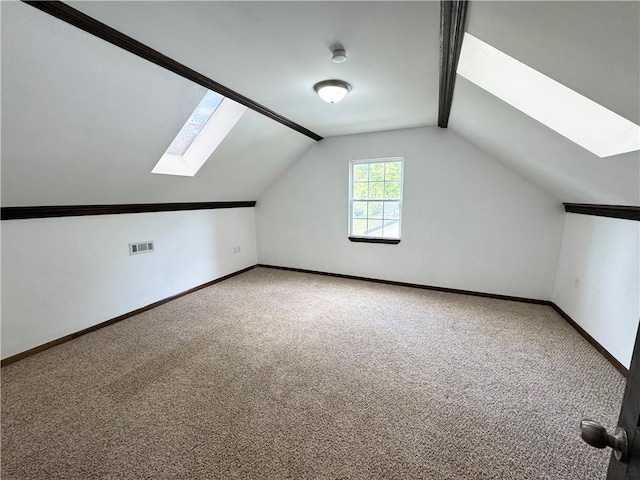 additional living space featuring carpet flooring and lofted ceiling with skylight