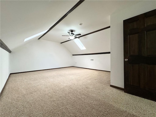 additional living space with vaulted ceiling with skylight, light colored carpet, and ceiling fan