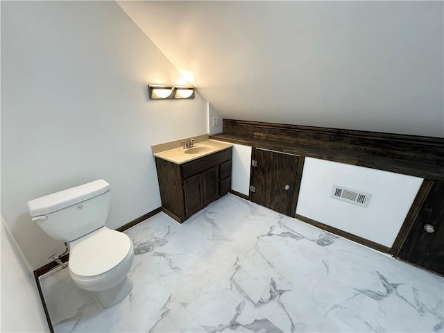 bathroom featuring lofted ceiling, vanity, and toilet