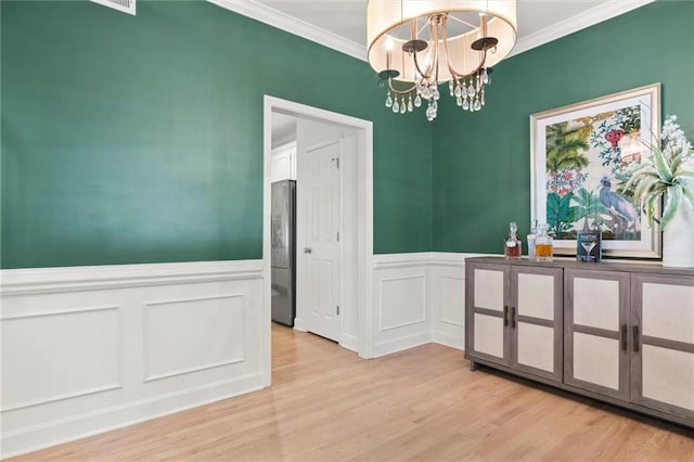 dining area featuring an inviting chandelier, light wood-type flooring, and crown molding