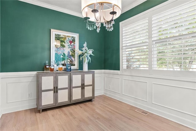 dining area with ornamental molding, a notable chandelier, and light wood-type flooring